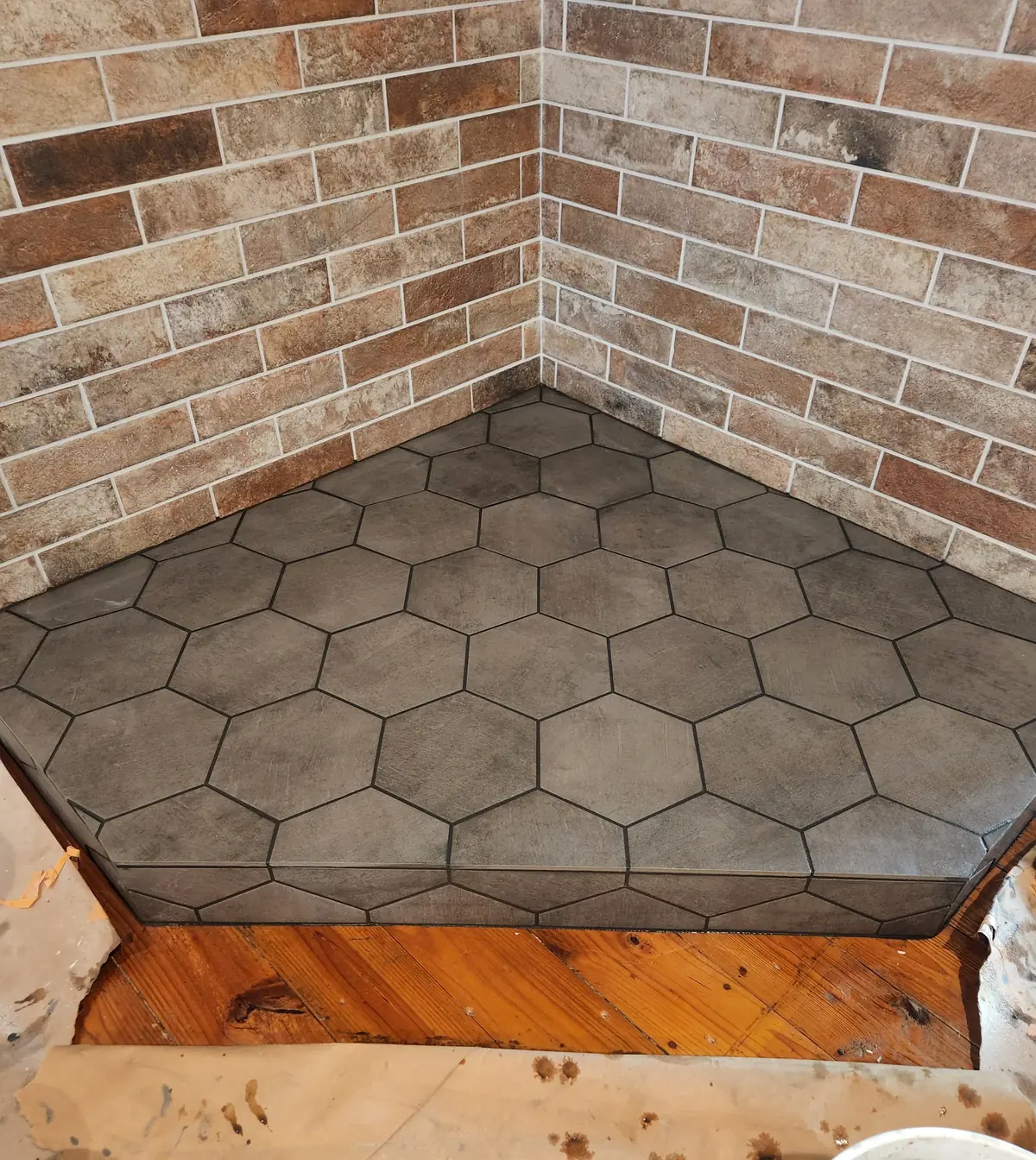 Brick accent wall meeting a hexagon tile floor