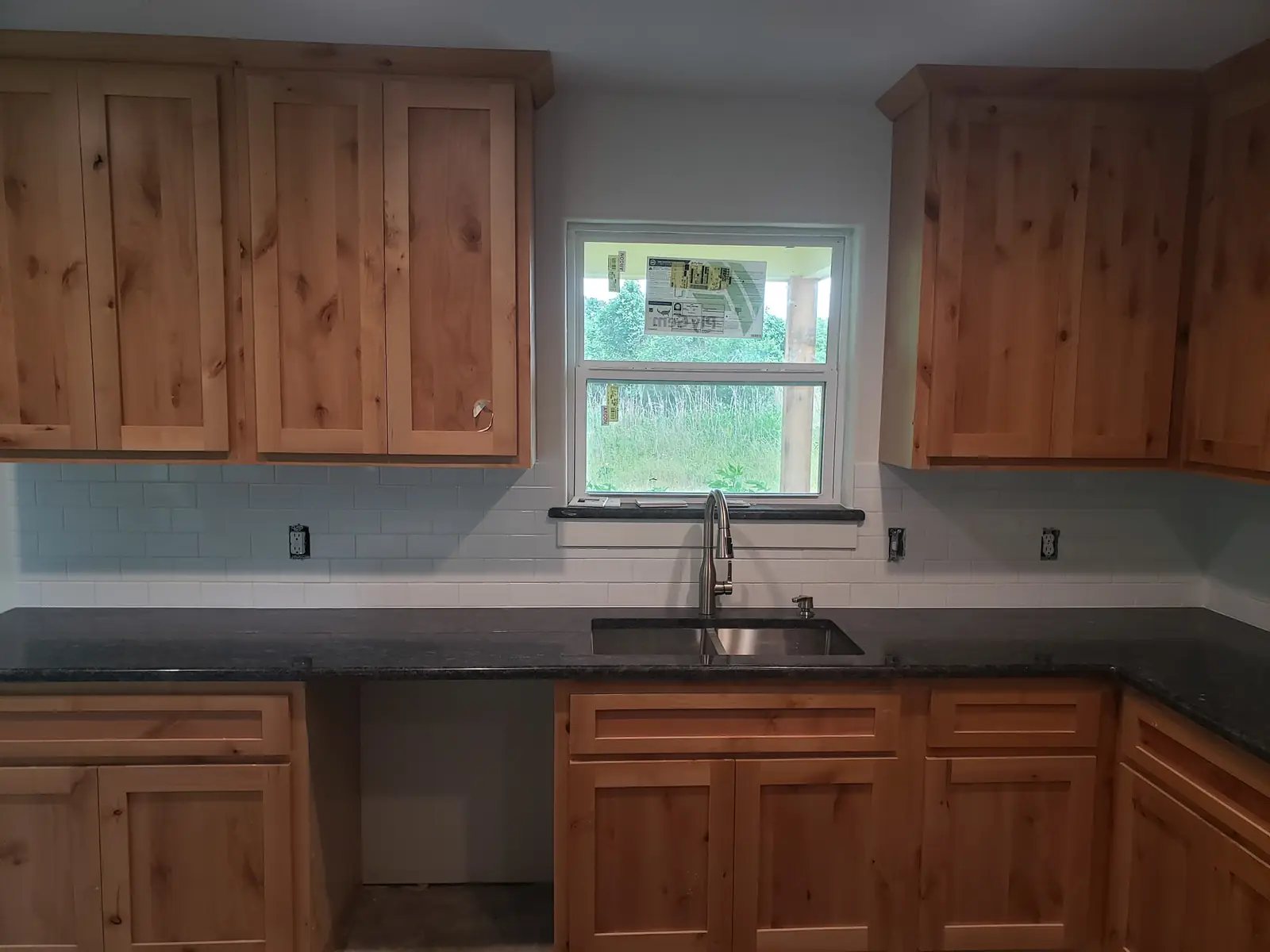 Dark countertop and tile backsplash on knotty alder cabinets