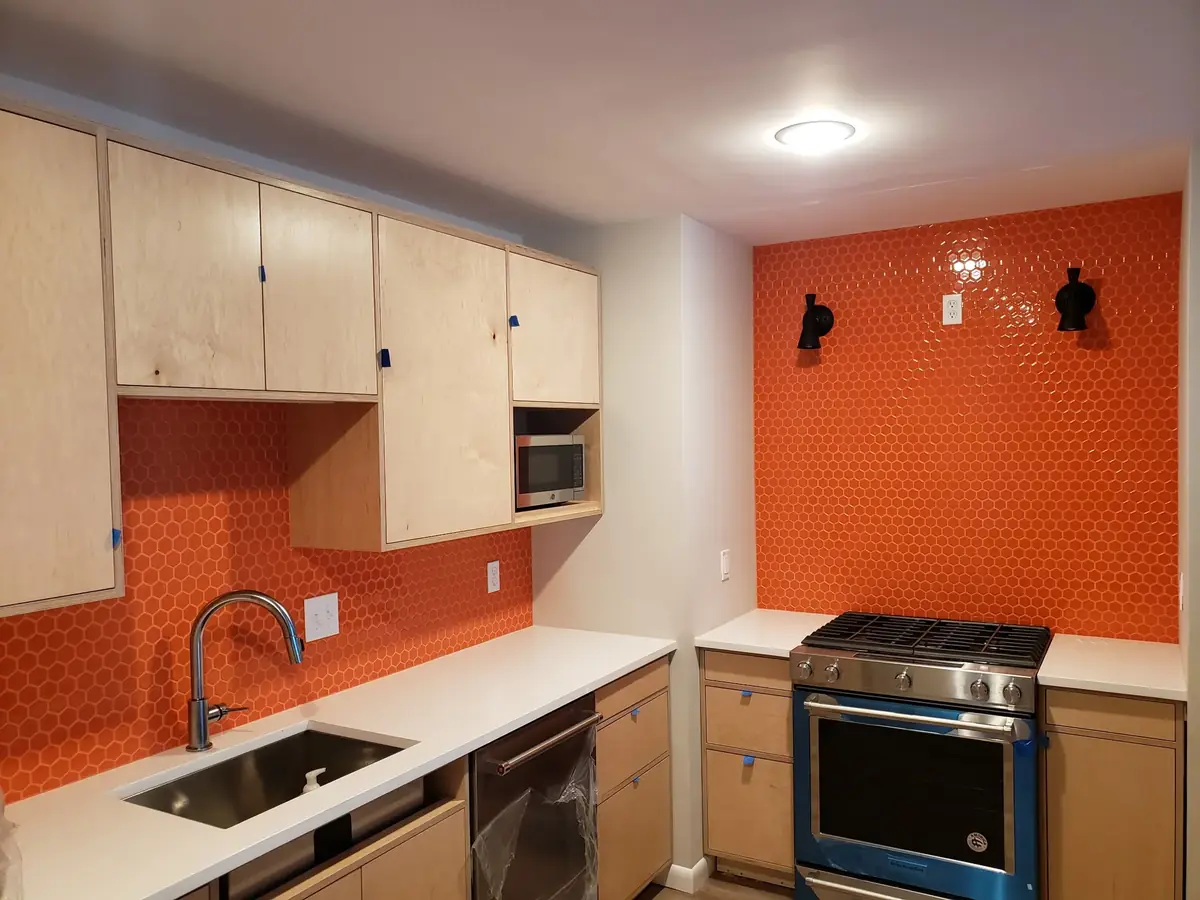 White quartz countertop with a bold orange tile backsplash