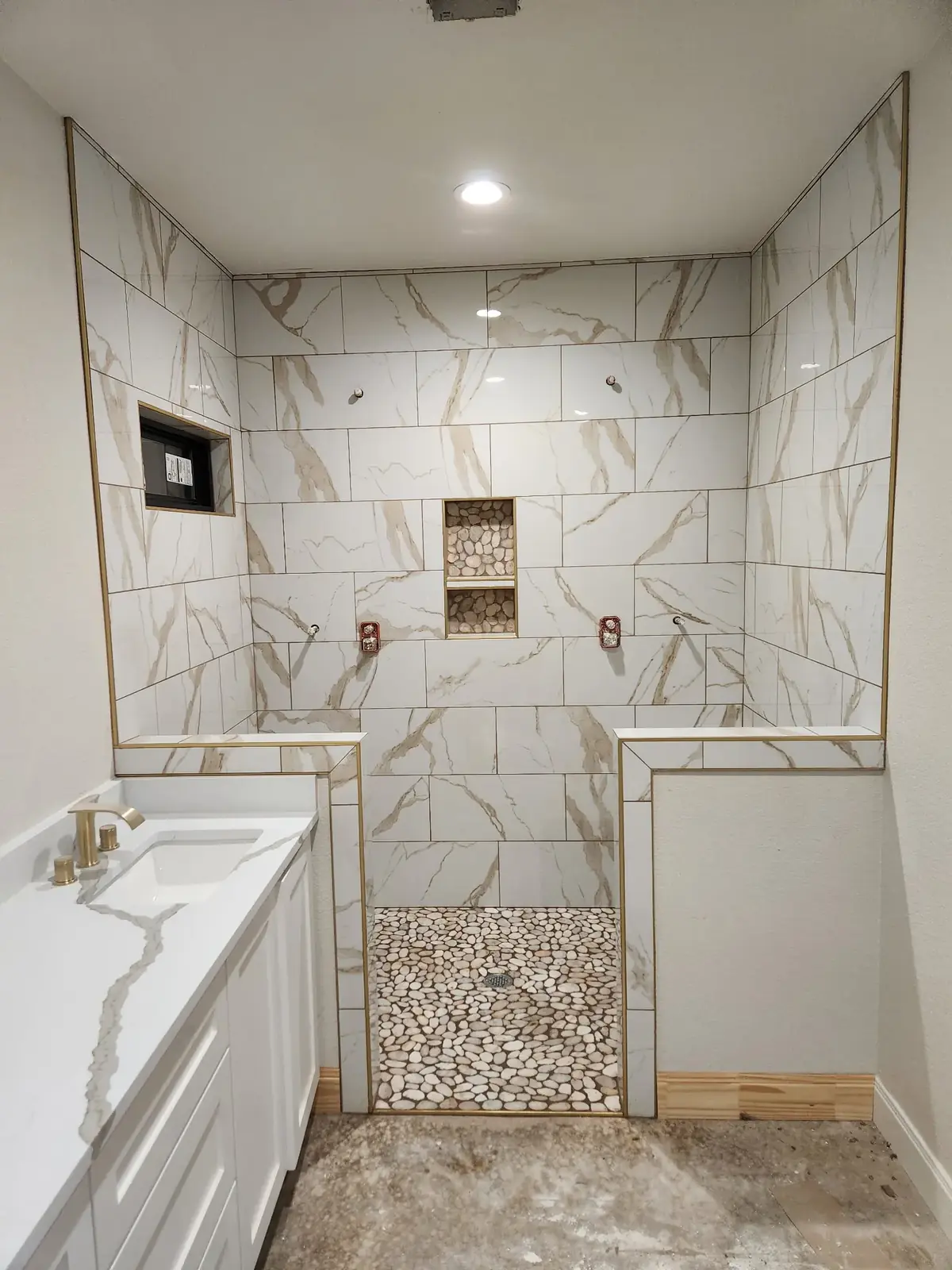 Marble-look tile shower with inset niche and gold trim