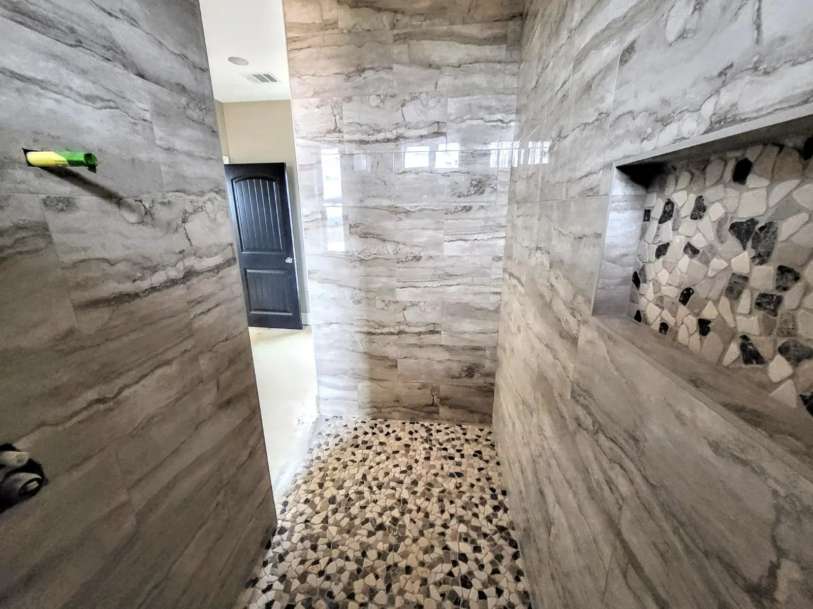 Stone-look tile shower with pebble floor
