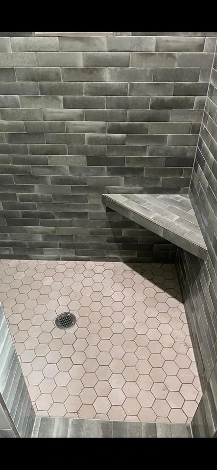 Gray tile shower with bench and hex floor